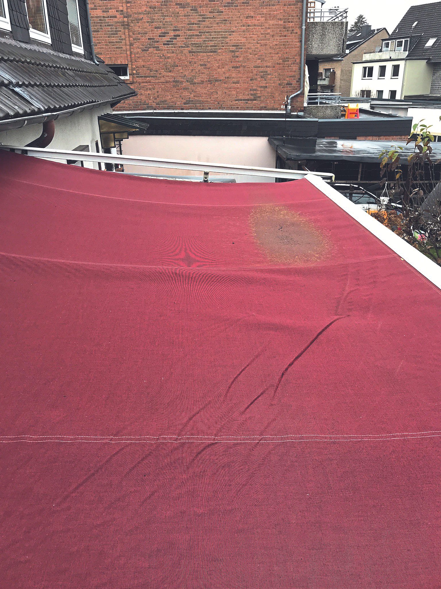 Auf dem Tuch sind deutliche Schmutzspuren von Wasseransammlungen erkennbar. Ebenfalls sind auf dem Tuch starke Knickfalten vorhanden.