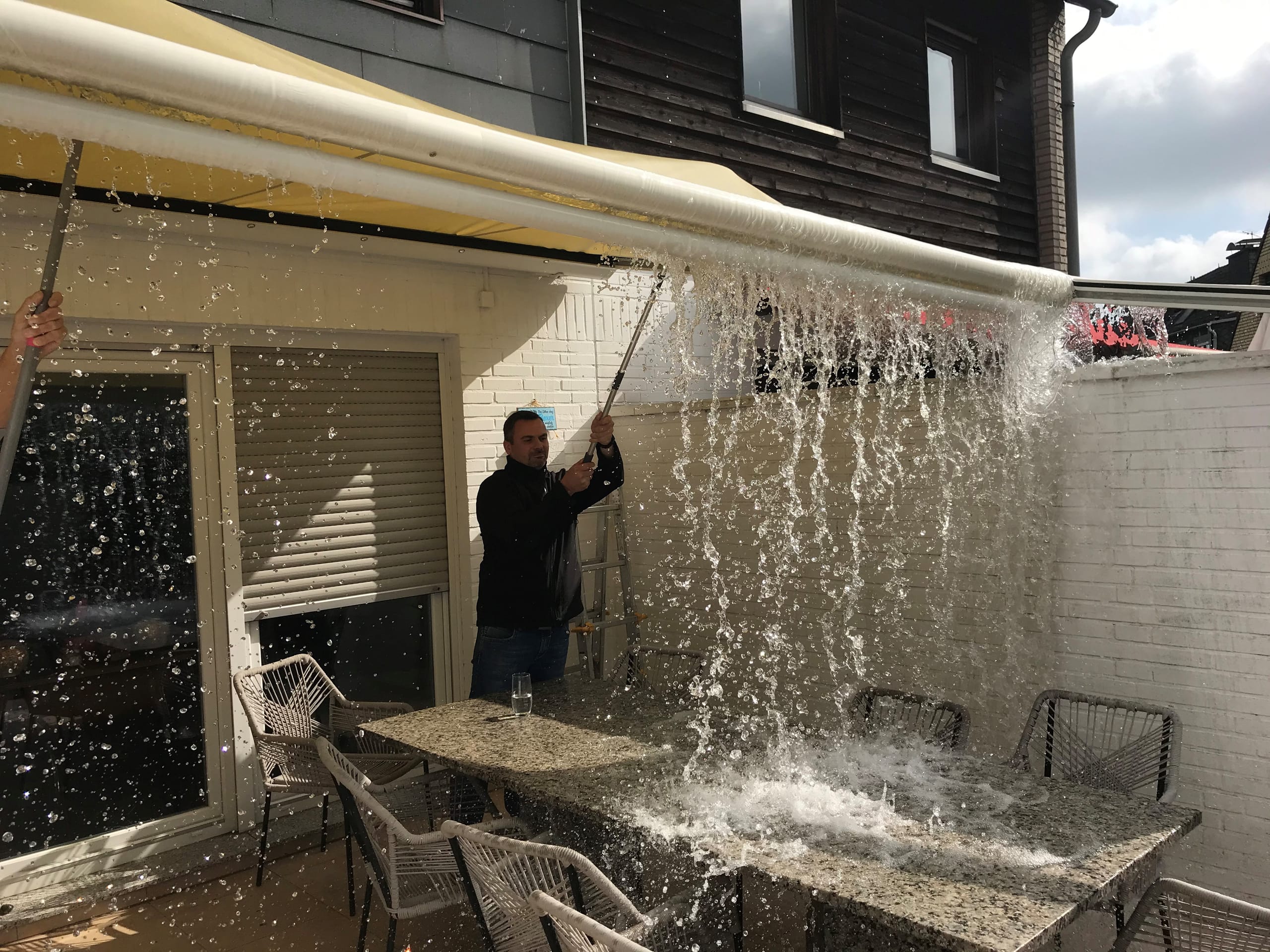 Mithilfe zweiter Besen drückten der Sachverständige und seine Helfer die Wassermassen vom Tuch.