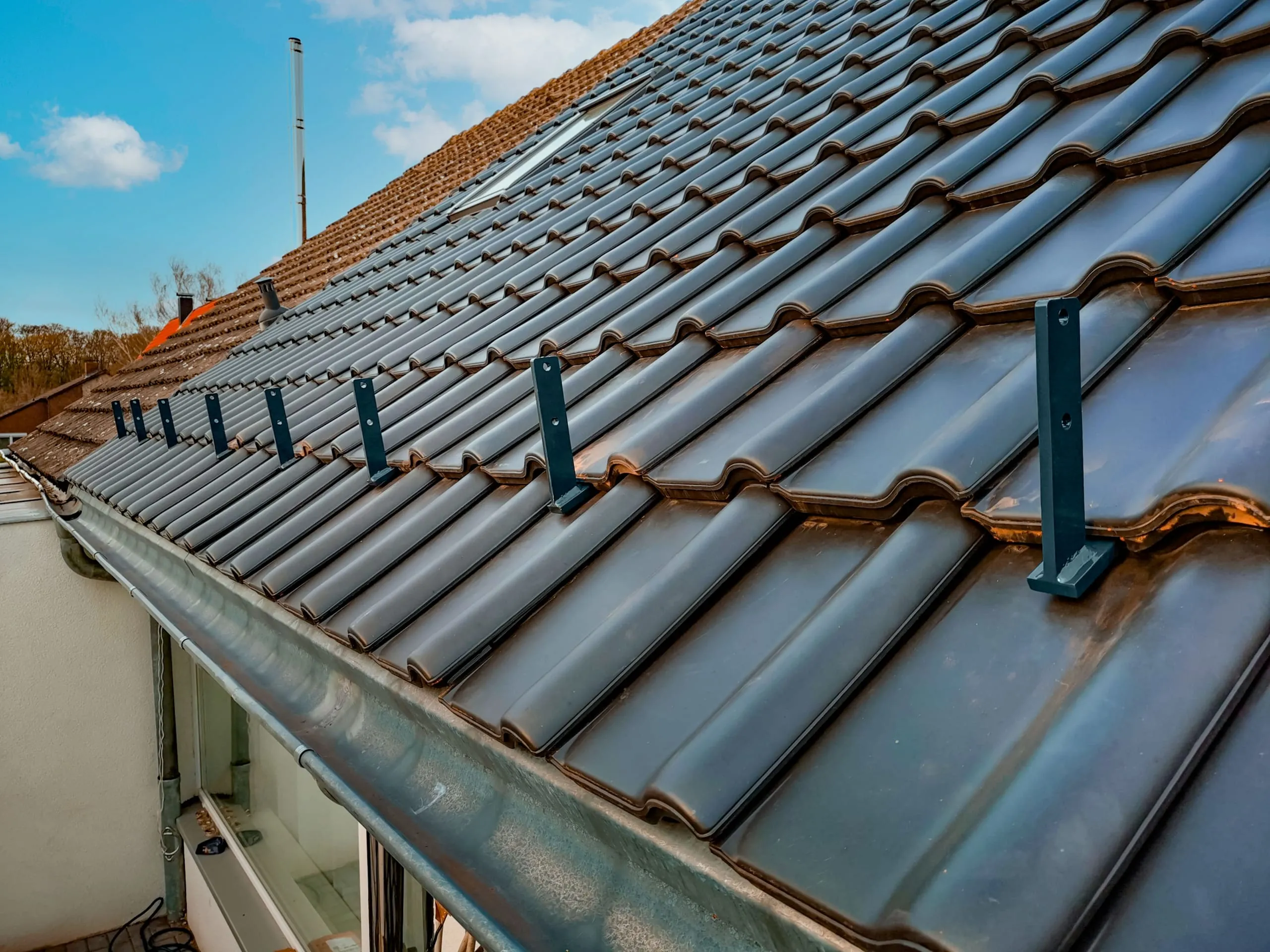 Auf jeden Sparren schrauben Sie einen Dachhalter, den Sie nach der Schnur ausrichten. Das Dach wird nun wieder eingedeckt. Dabei immer von unten nach oben arbeiten. Die Halter sind nun in das Dach integriert.