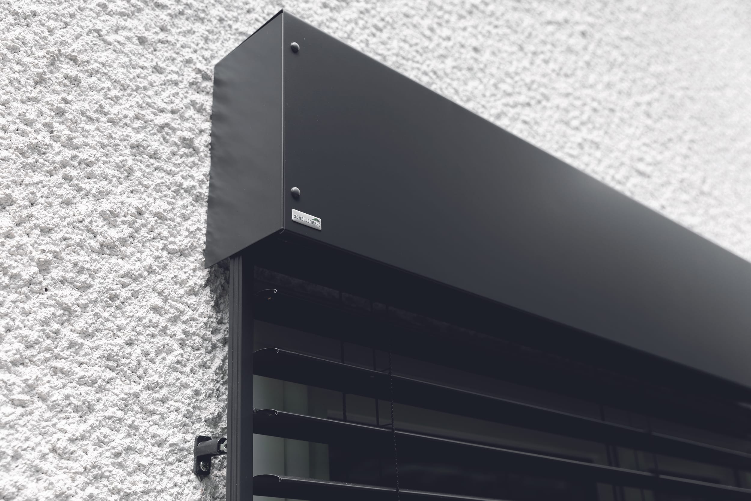 Bauen Sie die Kastenblende zusammen. Setzen Sie sie auf und verschrauben Sie sie von oben mit den Montagebügeln.