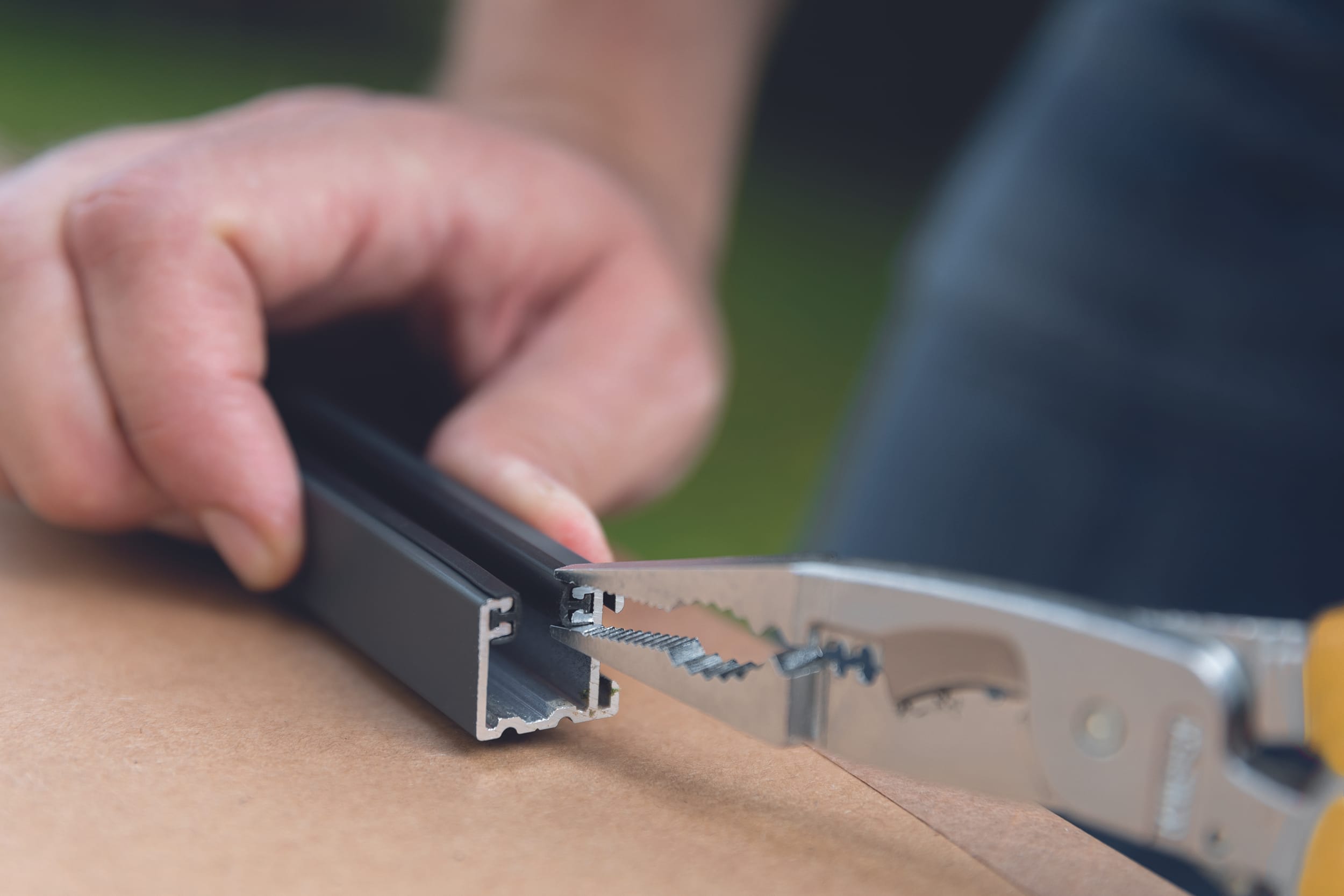 Drücken Sie beide Enden der Führungsschienen mit einer Zange zusammen, um den Gummikeder zu sichern.