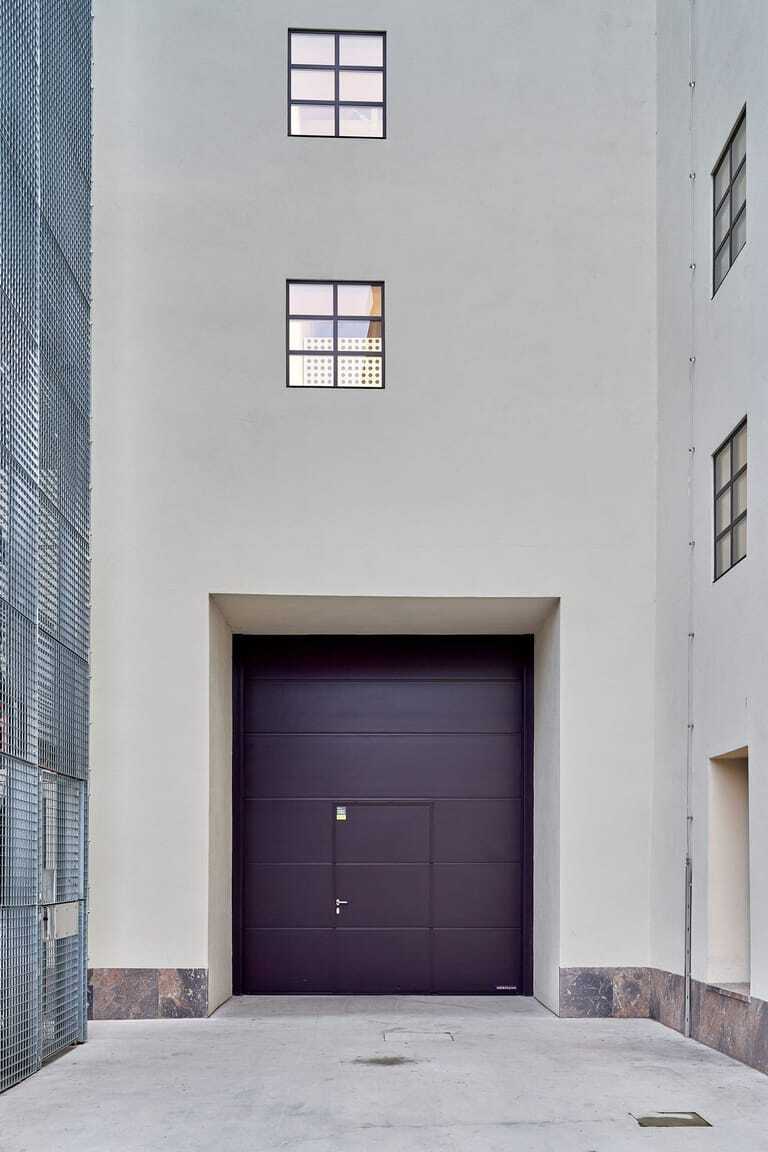 Mit der dunklen Farbgebung bildet das Industrie-Sektionaltor von Hörmann einen starken Kontrast zur hellen Betonoberfläche.