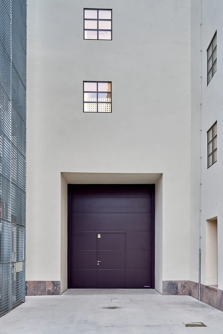 Mit der dunklen Farbgebung bildet das Industrie-Sektionaltor von Hörmann einen starken Kontrast zur hellen Betonoberfläche.