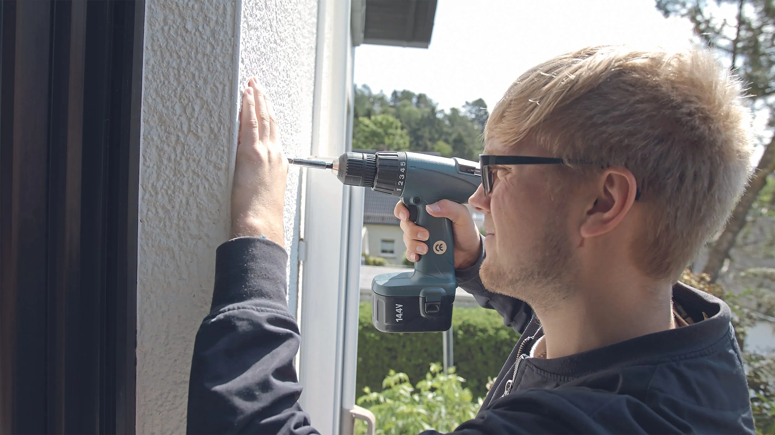 Hängen Sie den Antrieb noch einmal aus, damit genug Platz ist. Dann bohren Sie die markierten Löcher, stecken die Dübel hinein, hängen den Motor mit dem Haken wieder in die Öse ein und befestigen ihn mithilfe der Wandhalterung. Die passenden Schrauben liegen bei.