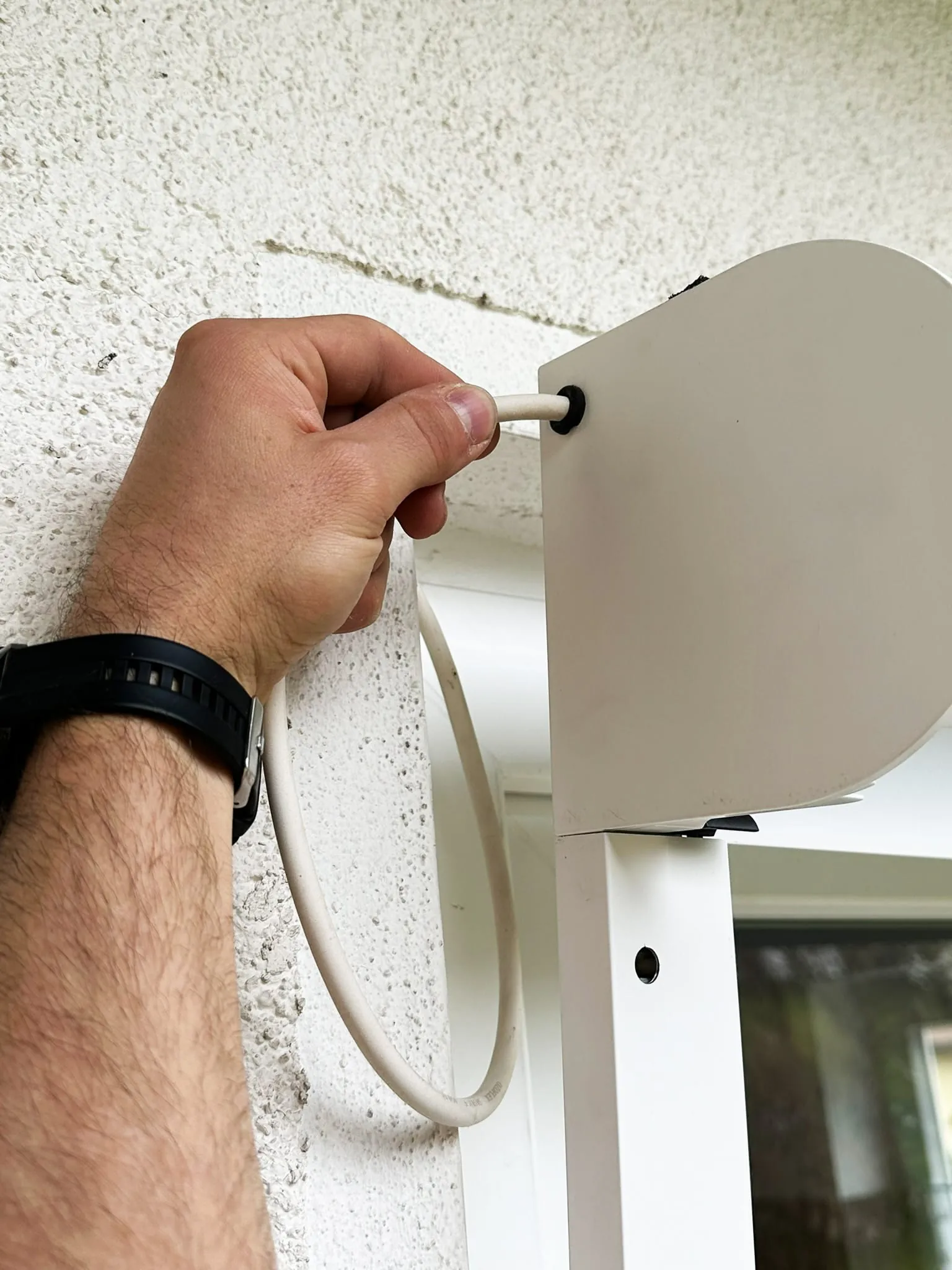 Setzen Sie das leere Vorbauelement an die korrekte Position an der Wand oder am Fensterrahmen. Achten Sie darauf, dass Sie die Antriebsleitung durch die dafür vorgesehene Kabeldurchführung in den Kasten führen. So lassen sich Schäden am Leitungsmantel vermeiden.