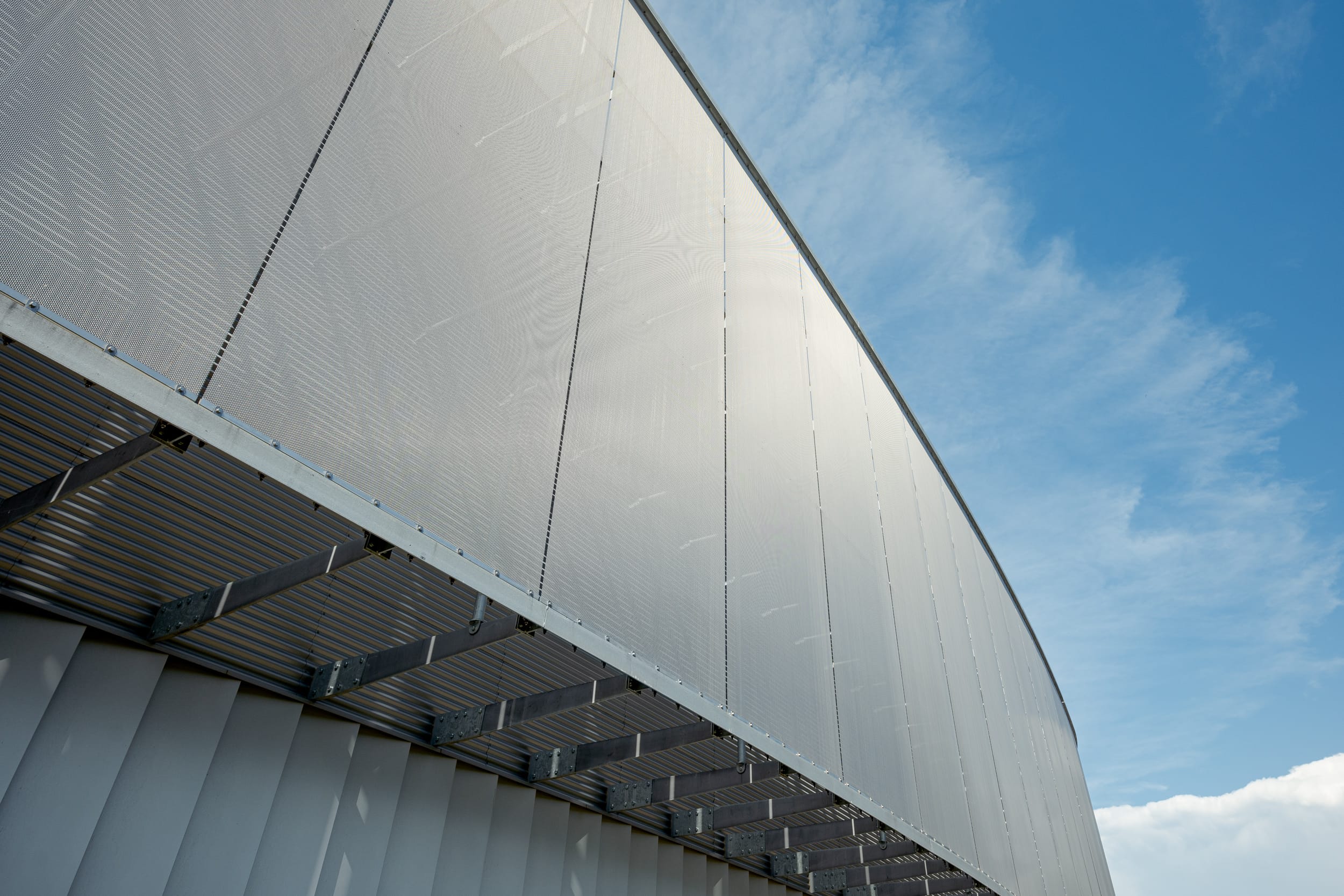 Das vom Architekturbüro Patriarche entworfene Gebäude vereine auf elegante Weise Funktionalität und Ästhetik. Die Metallgewebefassade erfüllt dabei gleich mehrere Zwecke: Sie fungiert als Sonnenschutz und verleiht dem Bau mit ihrer elegant schimmernden semitransparenten Oberfläche eine einzigartige visuelle Gestaltung.