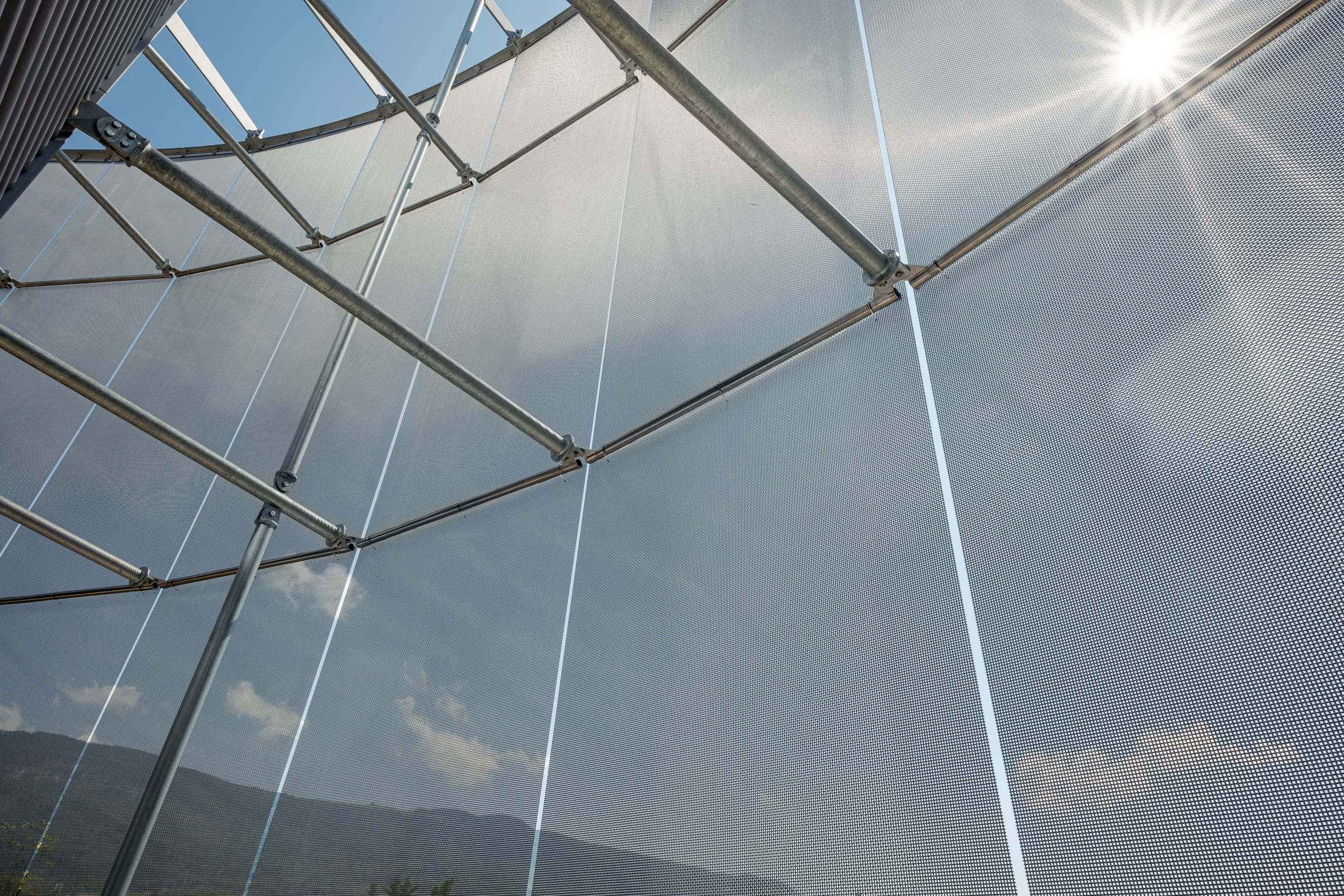 Neben dem Spiel mit Licht und Schatten, erzeugt das Edelstahlgewebe eine optisch leicht wirkende semi-transparenten Hülle, die je nach Sonnenstand unterschiedlichste Lichtreflektionen hervorbringt.