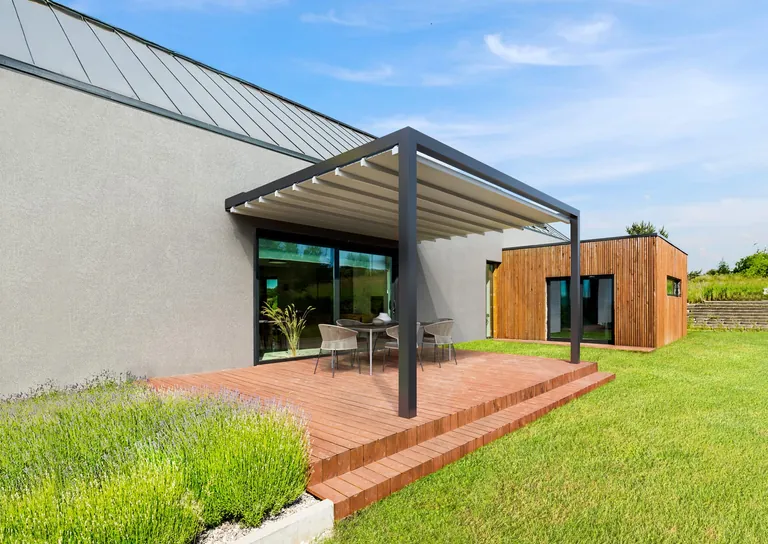 Die neue Pergola Lani kann an eine Glasfront angebaut werden und tr&auml;gt somit zu einer besseren Energieeffizienz des Geb&auml;udes bei.