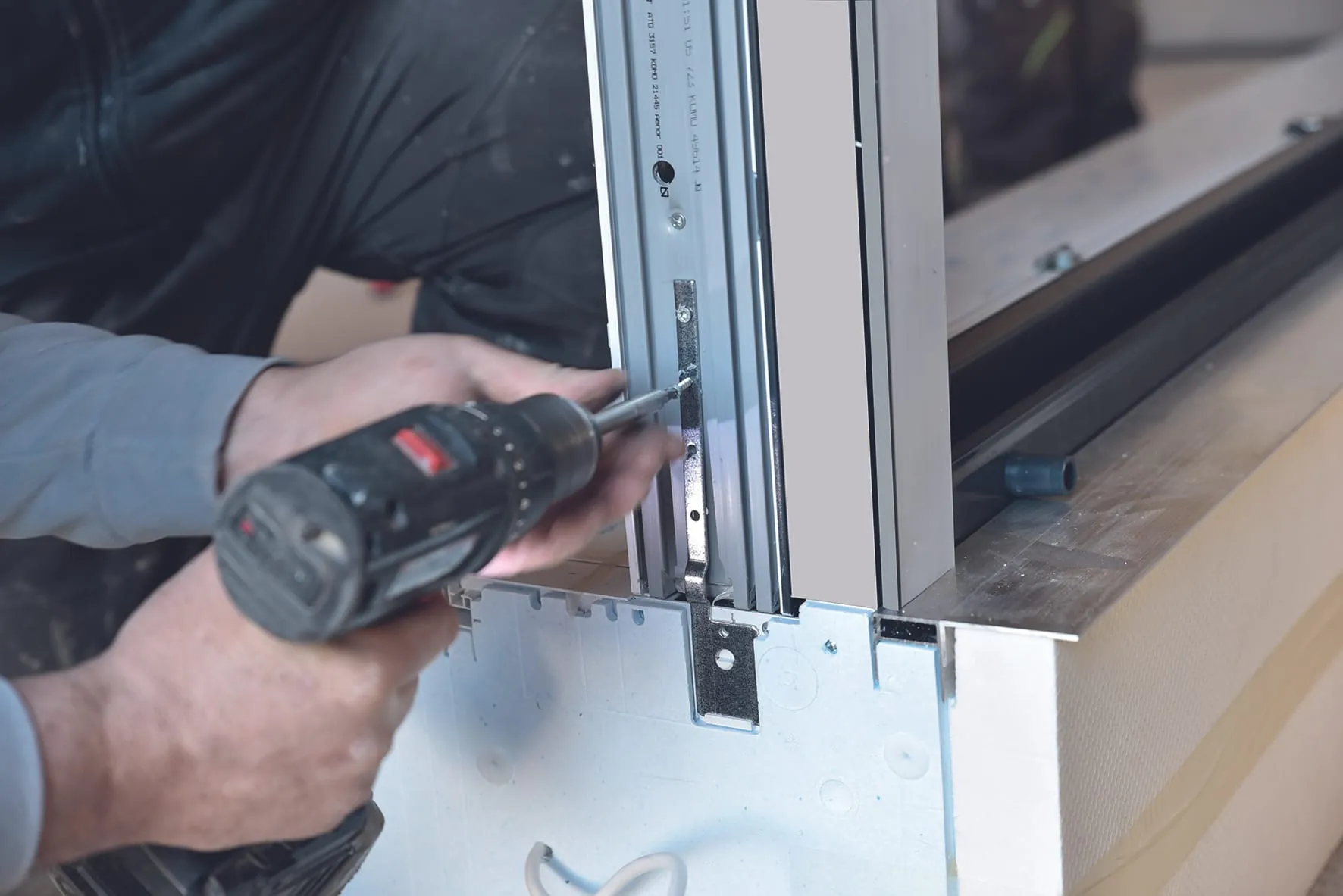 Stecken Sie die Befestigungsstiele an den Kopfstücken auf und verschrauben Sie sie mit dem Blendrahmen. Berücksichtigen Sie dabei den 90-Grad-Winkel des Kastens zum Blendrahmen.