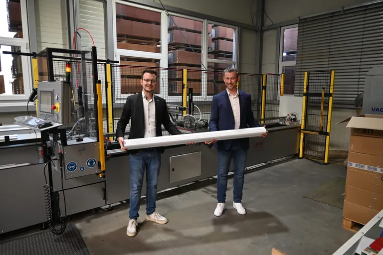 Tritscheler-Geschäftsführer Niklas Tritscheler (li.) und Acroloc-Geschäftsführer Benjamin Hoffmann (re.) vor der vollautomatischen Rollladenarretiermaschine E-Volet Plus.