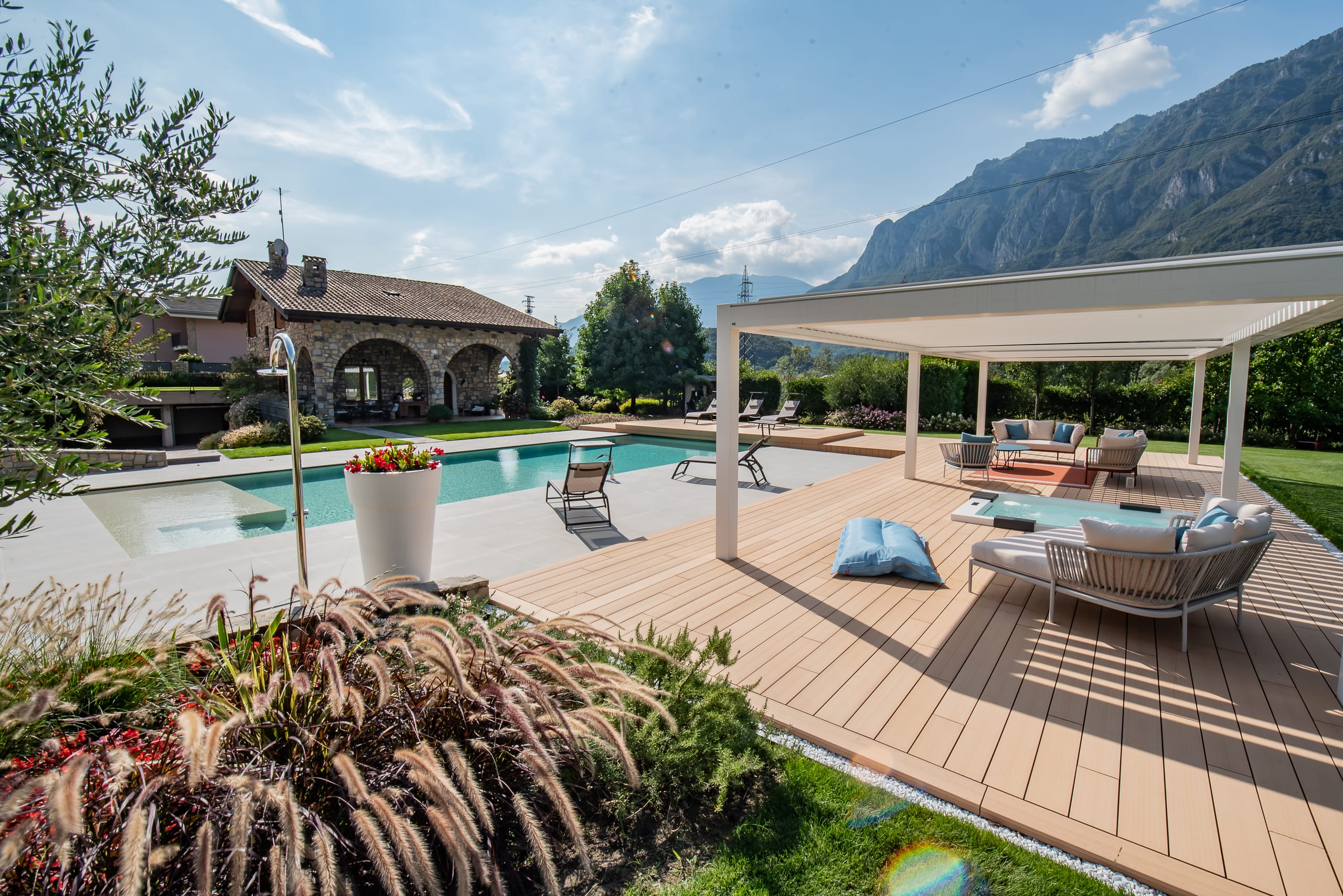 Der private Bauherr wünschte sich einen Raum, der Schatten, die Frische eines Pools und Komfort verbindet – abgestimmt auf die Architektur des Bestandsgebäudes und die umgebende Berglandschaft. Die überdachte Fläche beträgt 70 Quadratmeter, abgedeckt mit zwei bioklimatischen Pergolen und ergänzenden Vertikalbeschattungen.